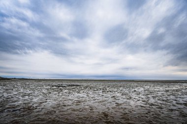 Norddeich, Almanya. 14 Temmuz 2025. Günbatımında Norddeich 'teki modern gezinti güvertesi, Wadden Denizi' nin gelgit sırasında gelgit düzlüklerine bakıyor. Huzurlu sahil güzelliği sessiz tasarımla buluşur