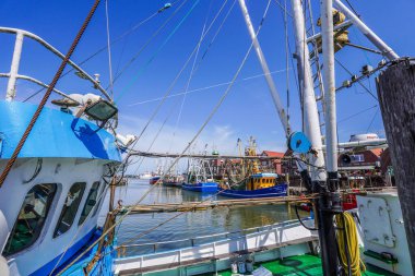 Neuharlingersiel, Almanya. 15 Temmuz 2025. Neuharlingersiel 'in pitoresk limanı demirli balıkçı tekneleri, geleneksel Doğu Frizya mimarisi ve gelgit düzlükleriyle. Kuzey Denizi 'nde denizcilik cazibesi uyandırıyor. (Tanımlanabilir isimler dijital olarak kaldırıldı)