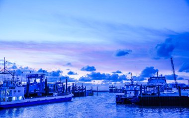 Norddeich, Almanya. 16 Temmuz 2025. Norddeich 'te tarihi bir liman ve gün batımında rıhtım boyunca tekneleri var. Günbatımında Doğu Frizya deniz mirası ve sahil cazibesi. (Tanımlanabilir isimler dijital olarak kaldırıldı)