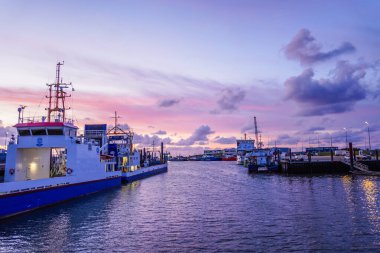 Norddeich, Almanya. 16 Temmuz 2025. Norddeich 'te tarihi bir liman ve gün batımında rıhtım boyunca tekneleri var. Günbatımında Doğu Frizya deniz mirası ve sahil cazibesi. (Tanımlanabilir isimler dijital olarak kaldırıldı)