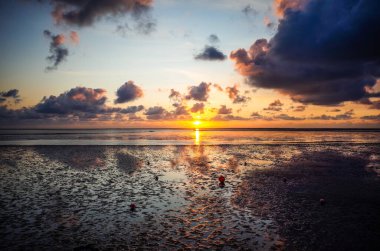 Norddeich, Almanya. 16 Temmuz 2025. Norddeich 'te romantik bir gün batımı. Sıcak renkler su ve gökyüzünü yansıtıyor.