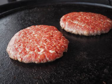 Taze çiğ köfte ızgaranın üzerine konmuş, klasik bir hamburgerle pişirilmeye hazır.