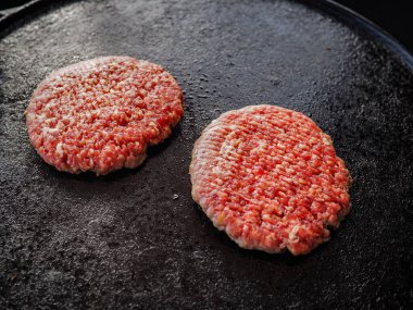 Taze çiğ köfte ızgaranın üzerine konmuş, klasik bir hamburgerle pişirilmeye hazır.