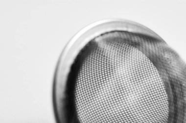 Çay süzgeci maşalarının siyah ve beyaz fotoğrafı, minimalist tasarımı vurgulamak, pratik çay demleme kullanımı ve zarif mutfak aksesuarları.