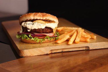 Patates kızartmalı burger, peynir ve tahta tahtada taze salata..