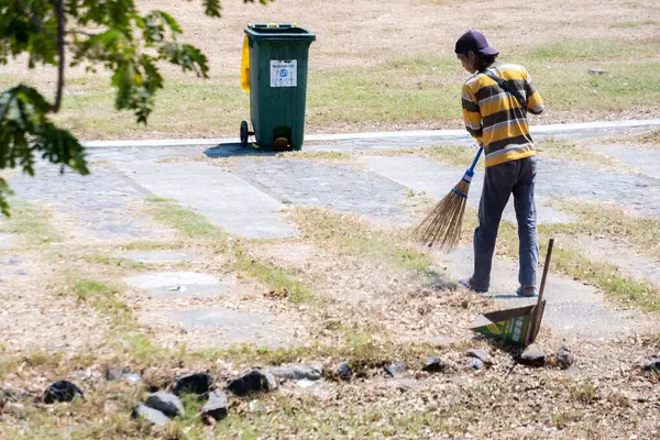 Yogyakarta, Endonezya - 11 Eylül 2024: Bir adam, çevre temizliği ve atık yönetiminin öneminin altını çizerek, kamu alanındaki çöpleri temizlemek için bıkmadan çalışıyor