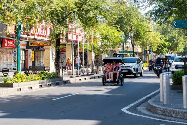 Yogyakarta, Endonezya - 12 Eylül 2024: Yabancı turistler sürekli sunulan motorlu çekçekle Malioboro Yogyakarta 'yı geziyorlar.