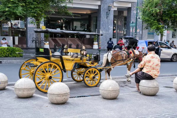 Yogyakarta, Endonezya - 11 Ekim 2024: Geleneksel Delman yolcuların Malioboro 'da bir çevrimiçi taksiden inişini izliyor, modern ulaşım hizmetlerini Jogjakartas klasik ulaşım cazibesiyle harmanlıyor.