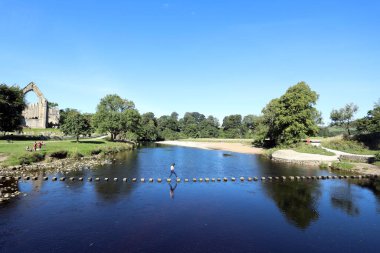 Kuzey Yorkshire, İngiltere 20 Eylül 2021. Arka planda Bolton Manastırı kalıntıları olan bir kadın rıhtımın karşısındaki basamaklarda yürüyor.