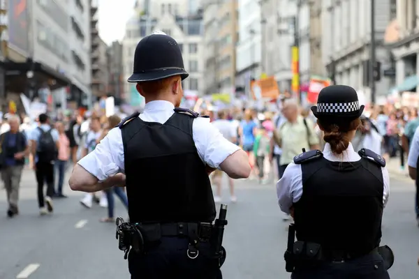 Londra, İngiltere 13 Temmuz 2018. Metropolitan Polis Teşkilatı 'nın iki üyesi, ABD Başkanı Donald Trump' a karşı Londra 'nın merkezinde düzenlenen protesto gösterisi öncesinde sohbet ediyorlar.