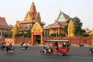 Merkez Phnom Penh, Kamboçya 'daki Wat Ounalom Tapınağı' nın önünden sabah trafiği hızlanıyor..