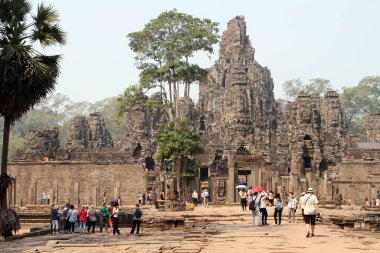 Turistler, günümüz Siem Reap, Kamboçya 'sının dışındaki Khmer imparatorluğunun eski başkenti Angkor Thom' daki Bayon tapınağına doğru yürüyorlar..