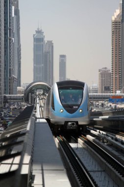 Yolcular Dubai, Birleşik Arap Emirlikleri 'ndeki Dubai metrosunun kırmızı hattındaki sürücüsüz bir trenin ön camından dışarı bakıyorlar. Şehir, daha fazla ilgi çekmek amacıyla çağdaş bir ulaşım altyapısına büyük yatırım yaptı.