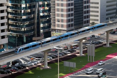 Dubai metrosunun kırmızı hattındaki bir tren Dubai, Birleşik Arap Emirlikleri 'ndeki Şeyh Zayed Yolu' nun yüksek binalarını ve trafiğini geçiyor.