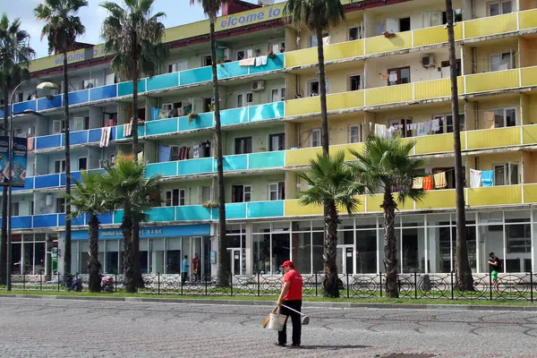 11 Eylül 2014 'te Gürcistan' ın batısındaki eski apartman bloğunun önünde bir sokak temizleyicisi yürüyor..