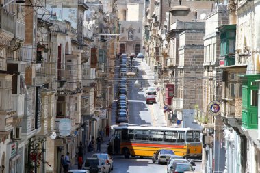 A bus tries to navigate through the narrow gaps on Triq il-Vitoria, on the Seglea peninsula in Valletta, Malta clipart