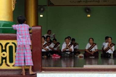 31 Aralık 2011 'de Shwedagon Pagoda, Rangoon, Burma' da (Myanmar) namaz kılan kadınları izleyen genç bir çocuk görülüyor.
