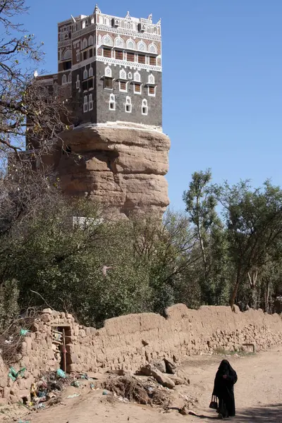 15 Kasım 2008 'de Yemen' deki Wadi Dhar 'da peçeli bir kadın imamın sarayının önünden geçiyor.