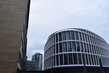 Bir üniversitenin modern binalarının dış görünüşü ve arka planda bir banka kulesi