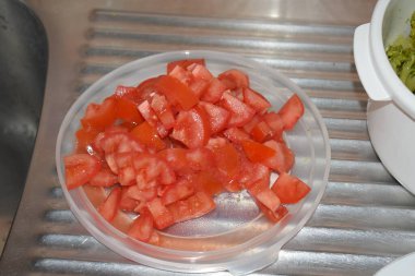 Mutfak masasındaki kasede kırmızı domates var.