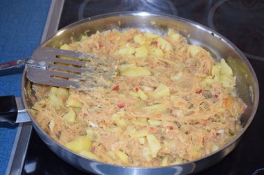 Tavada patatesle lahana turşusu kızartıyorum.