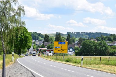 Trafik çemberi ve kırsal benzin istasyonu olan bir yol tabelası.