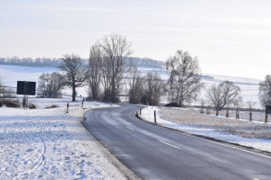 Kışın kır yolu beyaz karlı tarlalarla kaplı.