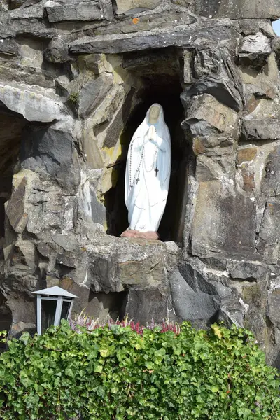 Yol kenarında park yeri olan beyaz bir Madonna ile mağara.