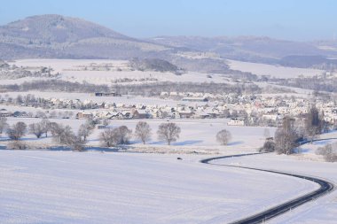 Köyde yolu olan bir kış manzarası.