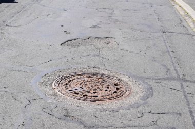 Eski paslı asfalt yolda delik var.