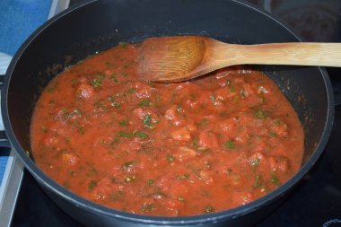 Tavada fesleğen ve domates sosu pişirmek..