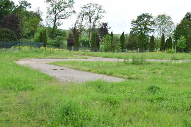 Eski terk edilmiş yollar, yeşil çimenler ve ağaçlar.