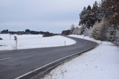 Karlı bir yolun karla kaplı bir ormanın güzel bir görüntüsü.