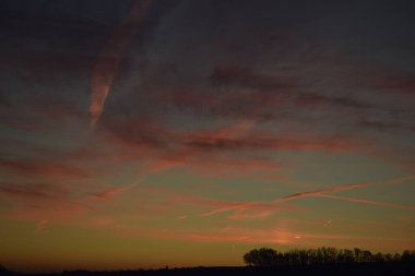 Arkasında kırmızı ve beyaz bir gökyüzü olan gün batımının güzel bir görüntüsü.