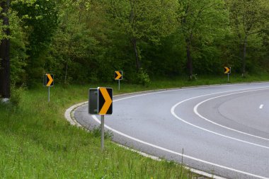 Yeşil ağaçlı bir yol tabelasının dikey görüntüsü