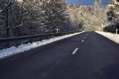 asphalt road in winter forest, road covered with snow. clipart