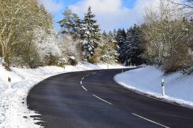 snow covered road with a forest clipart