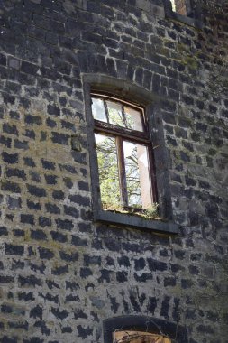 Bir pencere ve eski bir taş duvarla kaplı bir duvarın dikey görüntüsü.