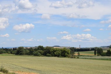 Ön planda tarlaları, çayırları ve ağaçları olan manzara