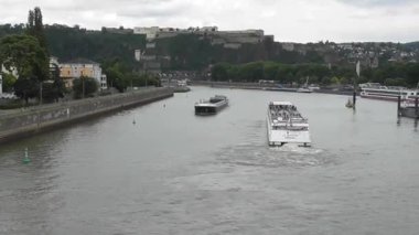 Koblenz, Almanya - 08 22 2025: Bir kargo gemisinin yanından geçen yolcu gemisi