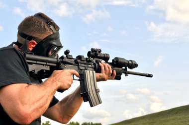 Gaz maskeli SWAT üyesi tüfeğini doğrultuyor.