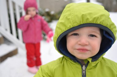Karlı bir gün ve genç çocuk arka planda kız kardeşiyle kameraya bakıyor.