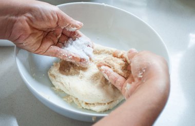 Bir kasede mısır unu yoğuran bir kadın.