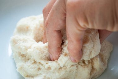 Bir kasede mısır unu yoğuran bir kadın.