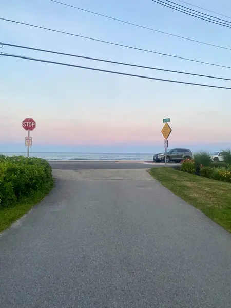 Plajda dur işareti olan bir yol bitiyor ve yakınlarda bir araba park halinde..