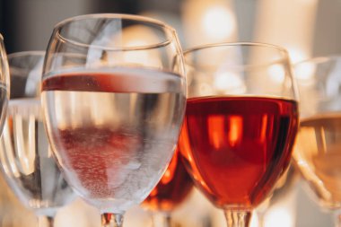 Farklı şaraplarla dolu bir sıra şarap kadehi.