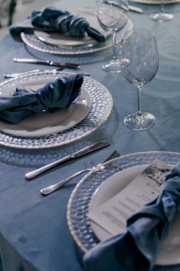 Tabaklarla süslenmiş güzel bir masa, zarif gümüş takımlar ve üzerine davetkar bir şekilde yerleştirilmiş şarap kadehleri.