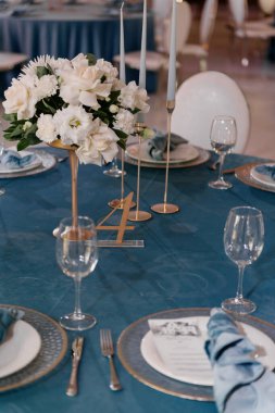 Zarif masa, zarif tabaklar, parlak mumlar ve onu süsleyen canlı çiçeklerle dolu bir düğün resepsiyonu için çok güzel hazırlanmış.