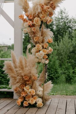 Güzel işlenmiş ahşap bir deste, canlı çiçekler ve zarif otlarla süslenir. Düğün töreni için göz kamaştırıcı bir ortam yaratır.