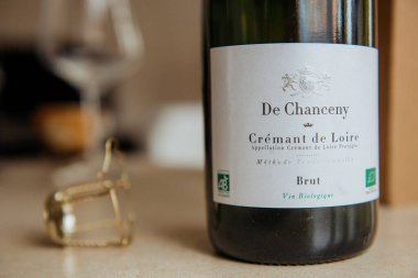 On a wellset dining table, a bottle of de chanceau is elegantly placed right next to a perfectly clear glass, ready for pouring